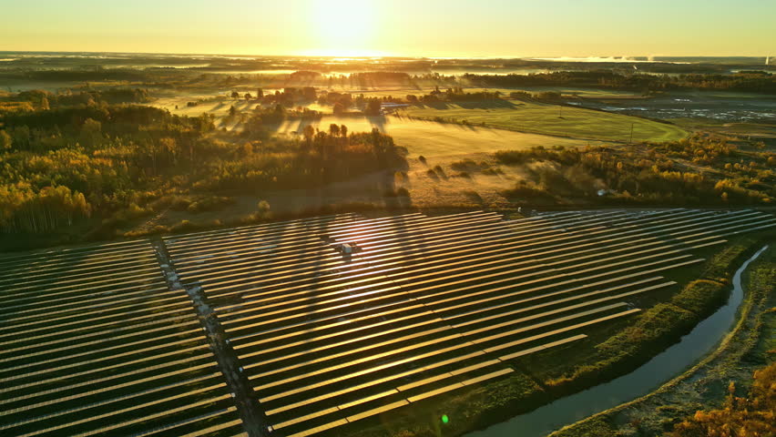 AERIAL: Beautiful autumn sunset behind a modern Photovoltaic energy farm