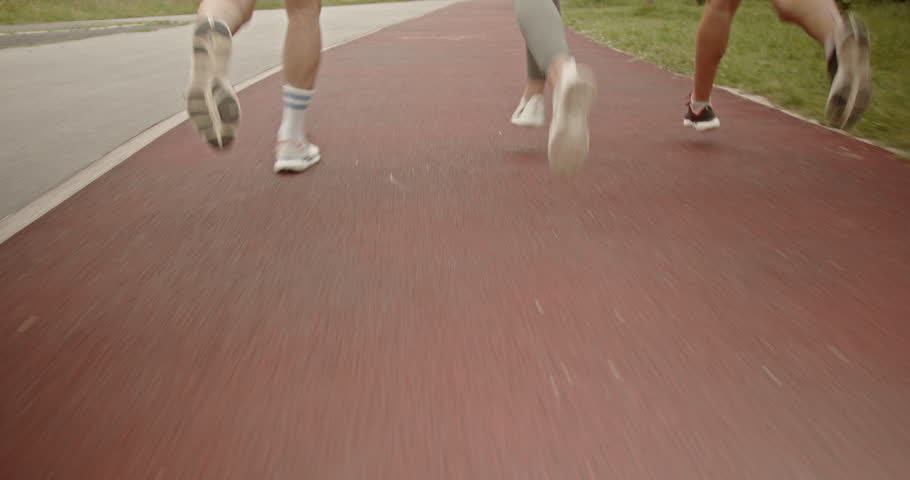Three friends jogging in the park. They are running on a red track and enjoying the benefits of an active lifestyle.