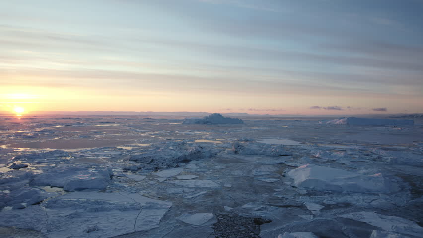 A mesmerizing aerial shot captures the uneven layers of icebergs and fragmented sea ice drifting together in the chilly waters of Greenland