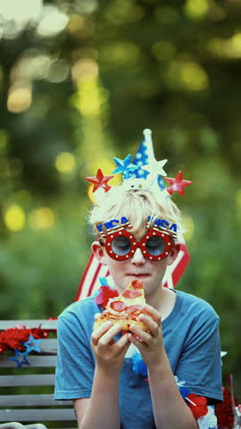A young boy dressed for the occasion enjoys pizza during a lively Fourth of July celebration