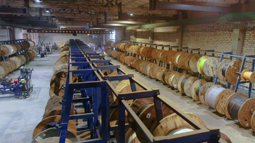 Large factory for the production of electric cable, intside. Production of electric cable. Warehouse with wooden reels of industrial cable. Production of electrical cable.