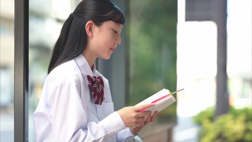 Japanese Junior High School Girl Reading Reference Book at Bus Stop