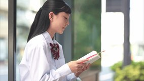 Japanese Junior High School Girl Reading Reference Book at Bus Stop - Powered by Shutterstock - Get 15% off with code: PIKWIZARD15