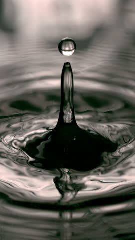 A water droplet splashes into the surface, creating stunning concentric ripples that radiate outward, showcasing the beauty of fluid dynamics