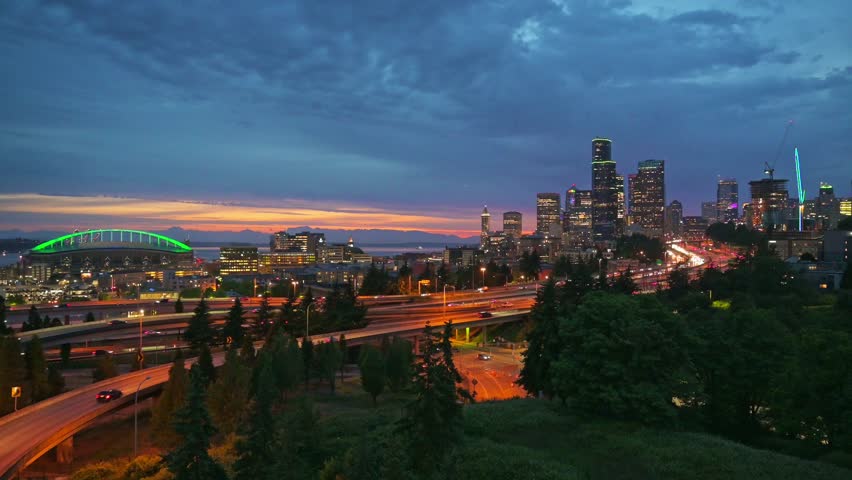 Sunset over the Seattle downtown skyline, with city lights, traffic and moving cars on the I-5 and I-90 freeway interchange. 4K UHD video.