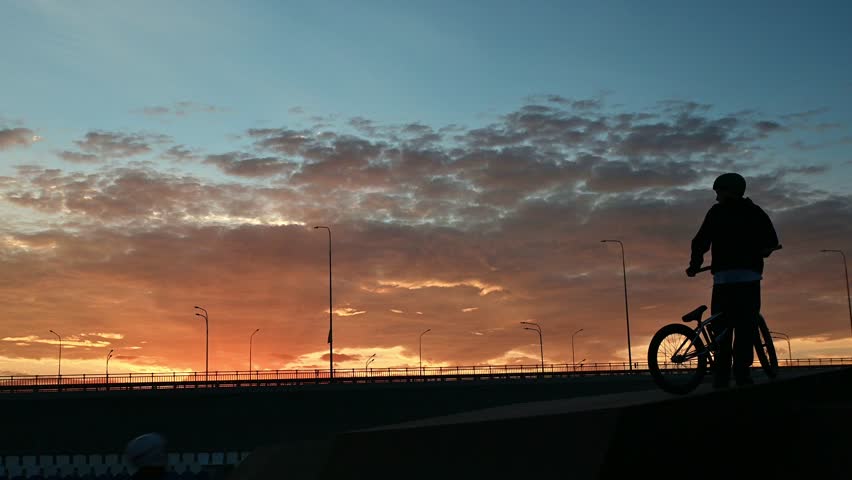 The athlete actively spends time at sunset. A cyclist rides on trampolines . A stuntman performs stunts on a bmx bike
