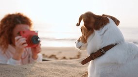 Woman photographs dog on beach sea summer dawn, capturing serene moment between pet and owner. Dog sits attentively, gazing at horizon warm light creates peaceful, memorable scene. Pet care. Lifestyle - Powered by Shutterstock - Get 15% off with code: PIKWIZARD15
