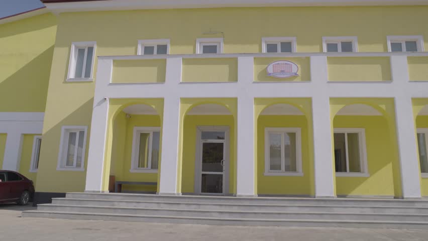Vibrant Young Couple Entering Yellow Building in Colorful Outfits, Daytime Scene