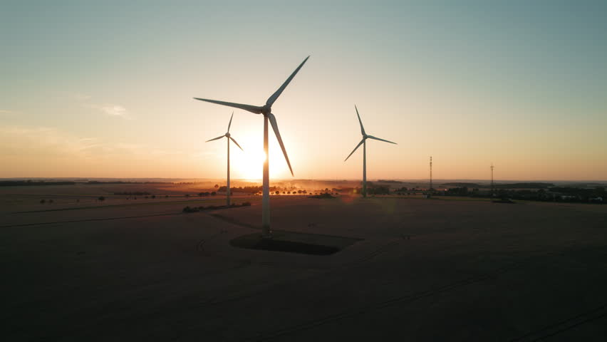 Fields with towering wind turbines bathed in soft sunlight, exemplifying renewable energy and natural beauty.