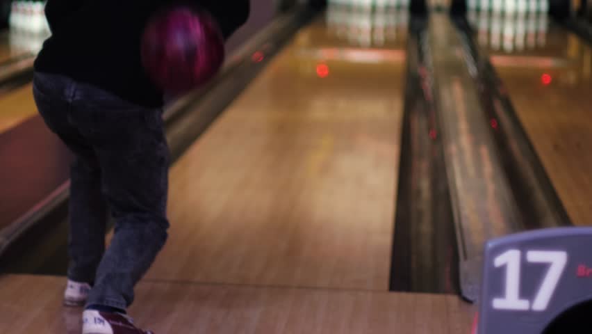 man playing bowling in club throwing ball into pins on playing lane, recreation and sports activities in bowling center, man throwing ball into pins in bowling alley