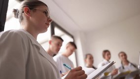 Group of young medical students in white coats attentively listening and taking notes during a lecture. Concept of education, teamwork, and professional training in the healthcare field - Powered by Shutterstock - Get 15% off with code: PIKWIZARD15
