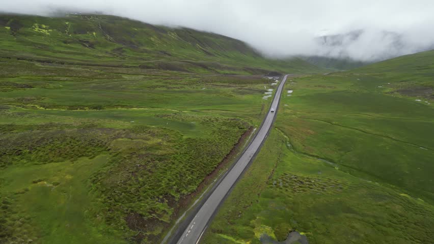 Aerial view of a mountain road in the arctic landscape of Iceland. The car is driving on the road in the tundra. High quality 4k footage