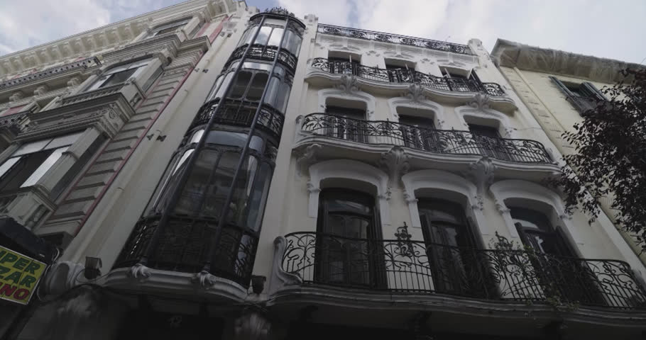 Beautiful slow motion zoom in shot of a classic building in the center of Madrid with trees around it on De Goya street in Madrid, Spain.