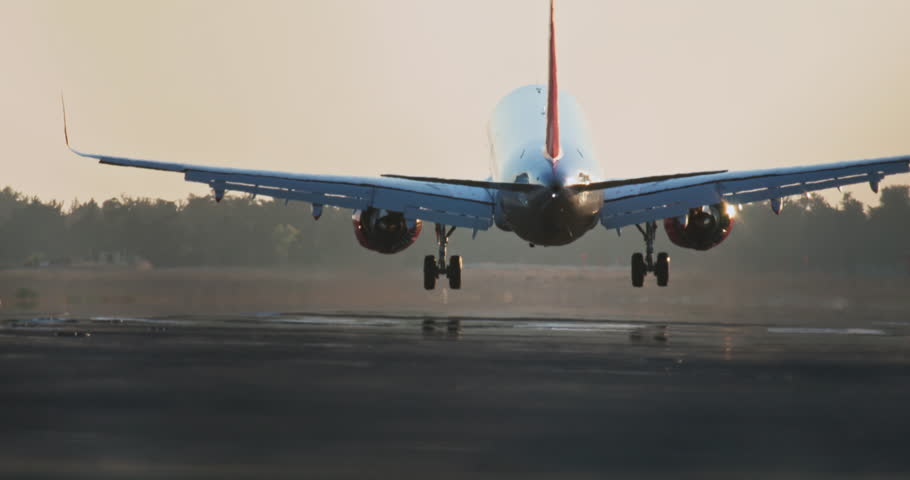 A passenger plane lands on the runway at sunset. Smoke comes from under the wheels of the airliner arrival slow motion video. High quality 4k footage