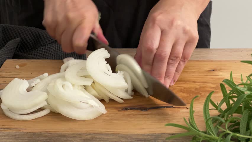 cook housekeeper chopping onion on wooden cutting board in kitchen. process of making homemade meal, cooking at home, food closeup
