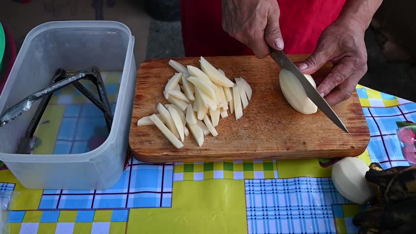 Detail of hands cutting potatoes at a Mexican street food stand