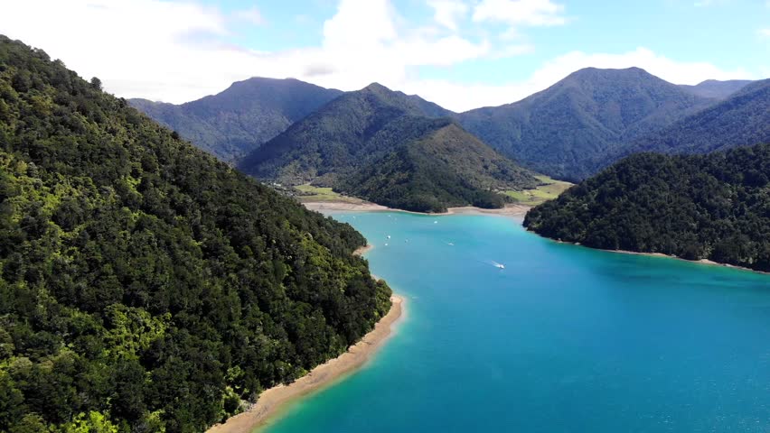 Fly over of Tennyson Inlet in the Marlborough Sounds on a clear summers day. Blue waters of the sound surroned by deep greens of the sub tropical rainforest.