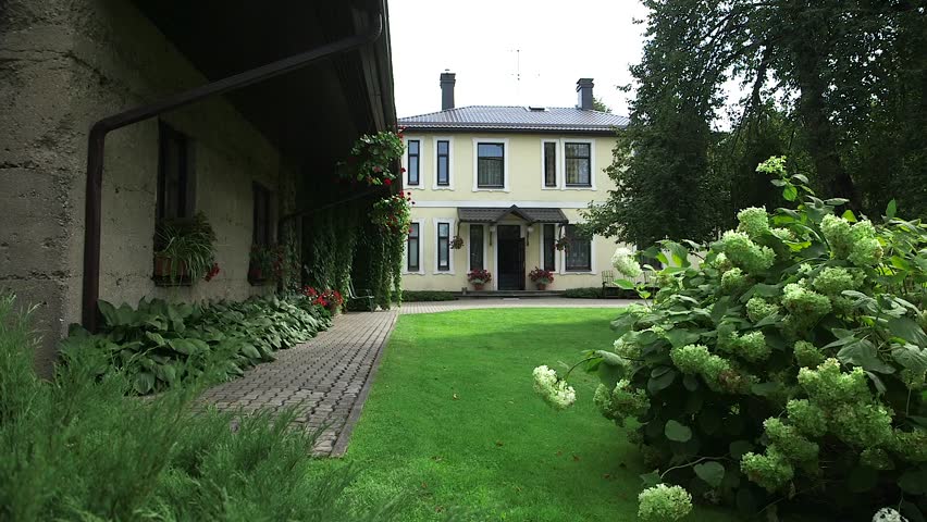 A Very Beautiful Backyard of a House with a Well-Kept Lawn, Lush Shrubs. A well-kept inner yard of the house creates a pleasant feeling for both the owners of the house and the guests.