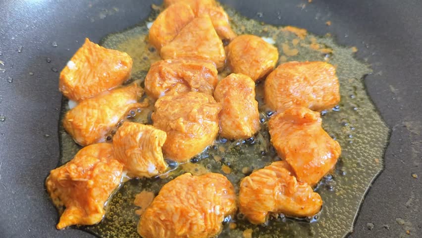 frying preparation of boneless pieces of chicken marinated in spicy masala with hot boiling oil in a pan 