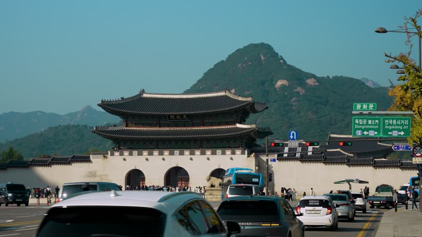 Seoul , South Korea - 10 24 2024: Cars drive On Sejongno Road Passing Famous Gwanghwamun Gate of Gyeongbokgung Palace in Seoul on Sunny Autumn Day, Bugaksan Mountain in Background