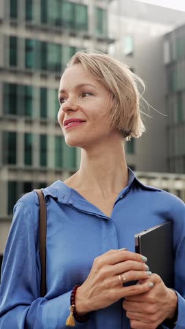 Confident business woman walking outdoors a modern office building. Portrait of young female corporate professional leaving the workplace after a successful day 