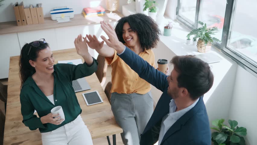 Video of business team celebrating good job while holding up their right hands on modern startup