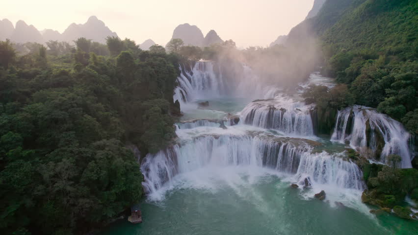 Aerial view of majestic Ban Gioc Waterfall, Detian Falls flowing amidst tropical forest during the sunset at Cao Bang, Vietnam