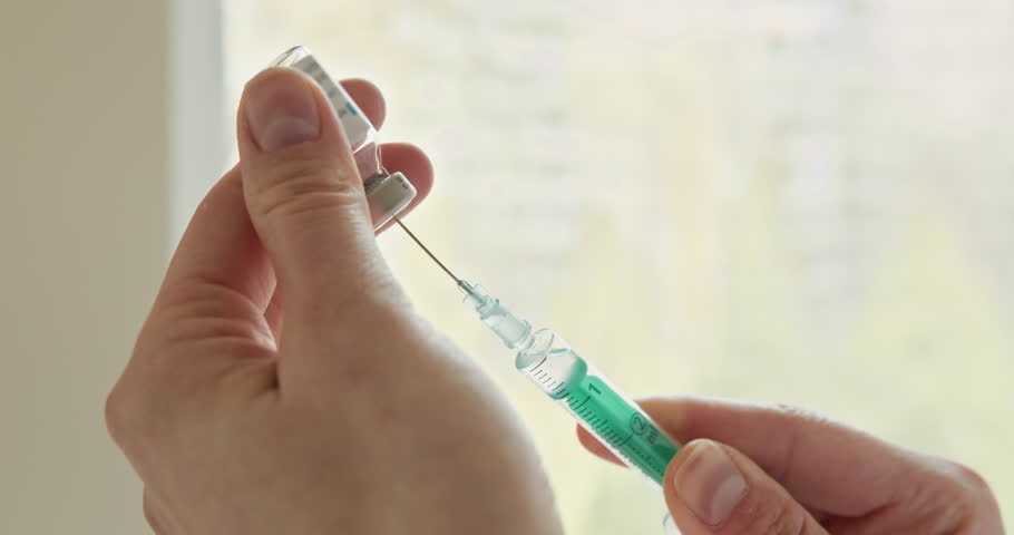 Preparing a Syringe for Vaccination or Medical Procedure is essential for patient care and safety. This is a closeup view of a hand carefully preparing a syringe, emphasizing its medical context