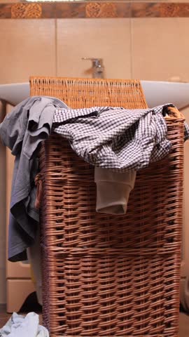 vertical video Clothes overflowing laundry basket with washing machine
