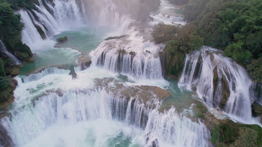 Aerial view of majestic Ban Gioc Waterfall, Detian Falls flowing amidst tropical forest during the sunset at Cao Bang, Vietnam