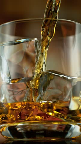Super slow motion of pouring whisky into glass . Filmed on high speed cinema camera , 1000 fps , vertical orientation