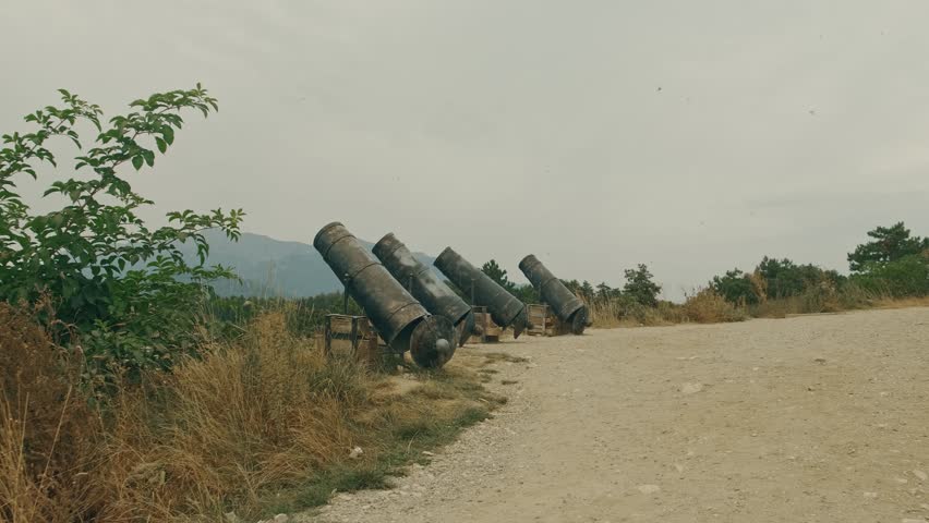 Exploring Rusty Cannons That Are Lining a Gravel Pathway Surrounded by Natures Beauty