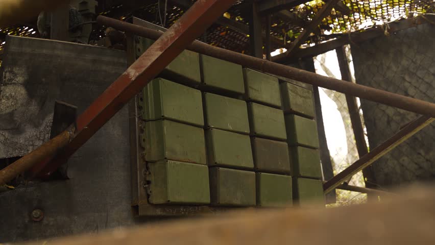Green armor plates on the side of a military tank, framed by metal bars and mesh. The protective plates are designed for extra defense in combat situations. heavy vehicle war in ukraine