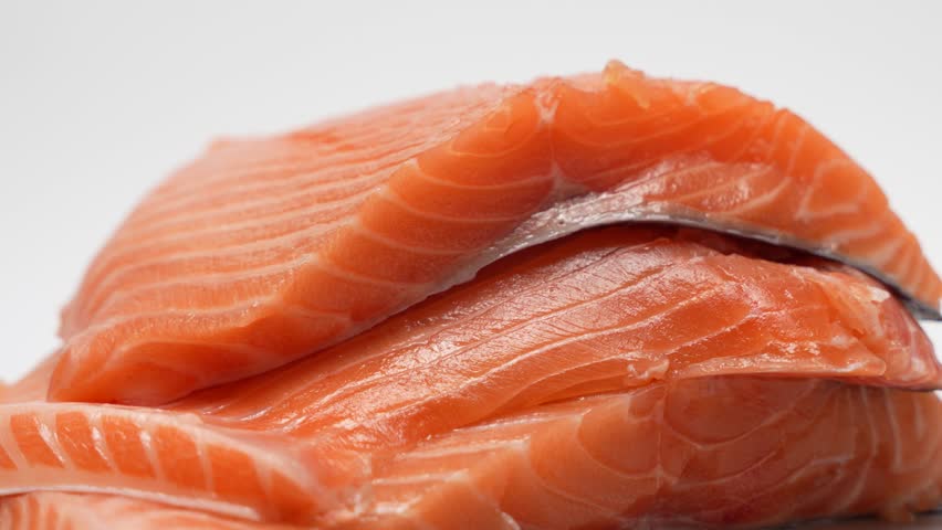 Rotating salmon fillet on a white background. The salmon is cut into slices and stacked. The concept of freshness and abundance as salmon is a healthy and nutritious food source.