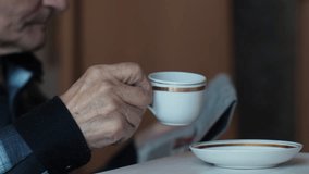 pensioner drinking coffee from cup and reading newspaper at home, Caucasian elderly man 70 years old drinking coffee for breakfast and reading fresh newspaper - Powered by Shutterstock - Get 15% off with code: PIKWIZARD15