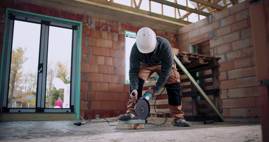Worker using angle grinder, sparks flying from metal cutting, indoor construction site, focused on safety and precision, protective helmet and gear