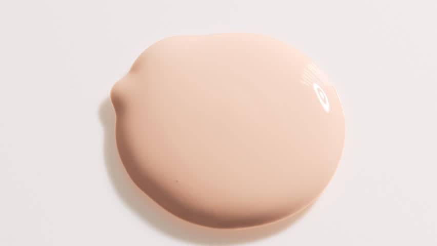 Smear foundation face make-up cream or beige concealer smudge with cosmetic spatula. Beauty texture background.