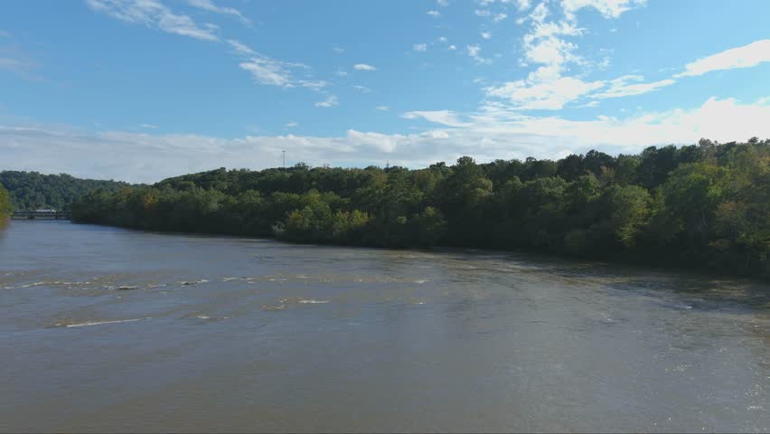 aerial footage of the silky brown waters of the Chattahoochee River surrounded by vast miles of lush green trees with blue sky and clouds at the Cochran Shoals Trail in Marietta Georgia USA