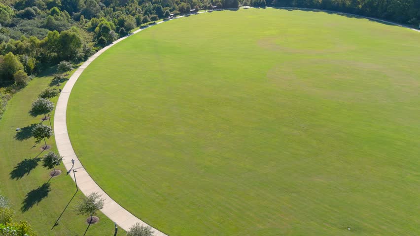 aerial footage of a gorgeous autumn landscape at Etowah River Park with lush green trees, grass and plants and cars parked in the parking lot and a gorgeous clear blue sky in Canton Georgia USA