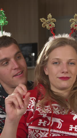 CLOSE UP: Cheerful man surprises his beautiful lady with a Christmas snow globe. Young couple in festive mood celebrating Christmas holidays and enjoying relaxing time together in home living room.