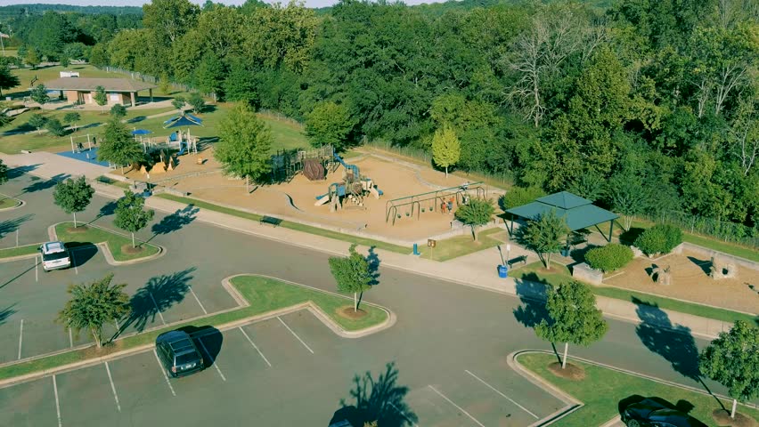 aerial footage of a gorgeous autumn landscape at Etowah River Park with lush green trees, grass and plants and cars parked in the parking lot and a gorgeous clear blue sky in Canton Georgia USA