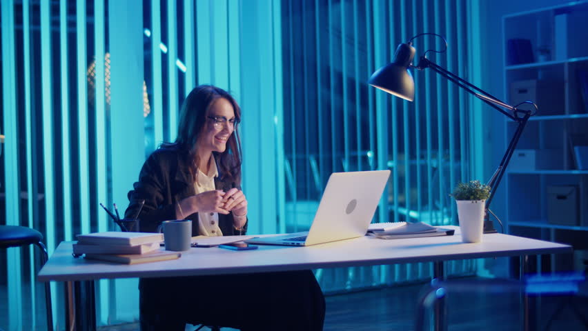 A Successful Businesswoman Hosts an Evening Online Meeting from Her Modern Office Concept of Leadership, Remote Collaboration in a Contemporary Work Environment Focus on Professional Success