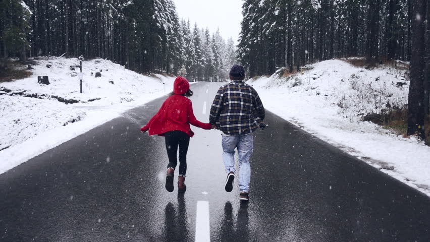 Cute Couple Having Winter Forest Date. Woman man run towards snowy forest holding hands and smiling. Enjoy winter holiday vacation together. Love relationship concept. Mixed race couple dating outdoor