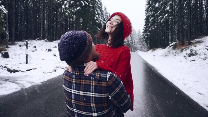 Cute happy Couple Having Winter Forest Date. Woman man whirl and hug towards snowy forest smiling. Enjoy winter holiday vacation together. Love relationship concept. Mixed race couple dating outdoor