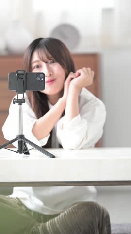 Image of video streaming by streamer. Cute young Japanese woman waving to camera.