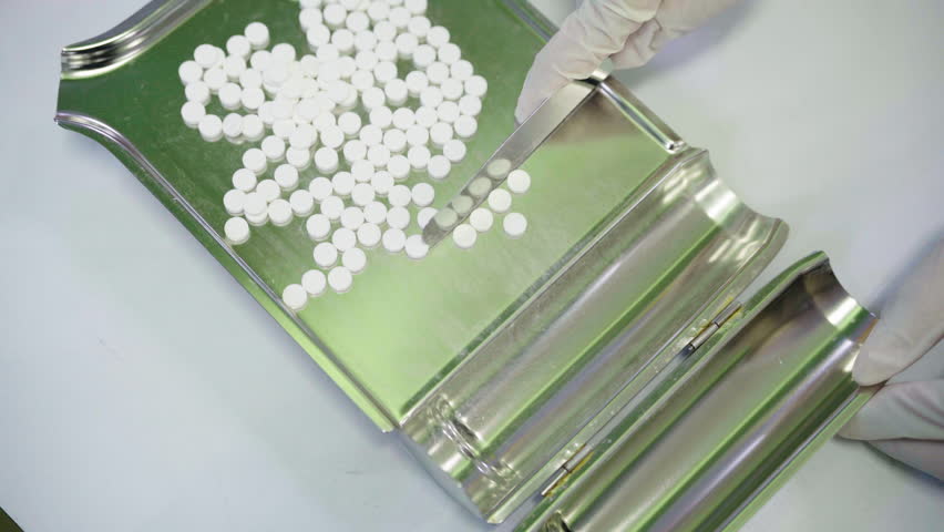 White pills are being selected for distribution.