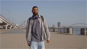 Cheerful attractive bearded African American man with backpack walking down embankment street, enjoying leisure and scenic view on sunny summer day in city. - Powered by Shutterstock - Get 15% off with code: PIKWIZARD15