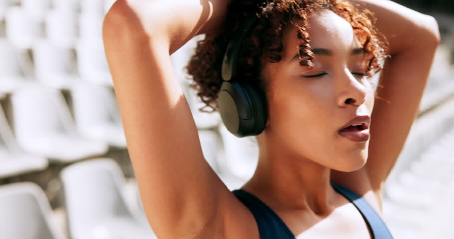 Runner, woman or breathing with headphones at stadium for race, sprint or workout preparation. Young, female person or calm athlete with music for relax exercise, training or getting ready in fitness