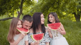 Joyful caucasian family with two little daughters eating watermelon outdoors. Young parents with kids spending free time together for picnic. Joyful family with kids eating watermelon outdoors. - Powered by Shutterstock - Get 15% off with code: PIKWIZARD15