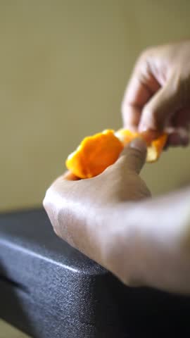 beautiful vertical video portrait a man's hand is peeling a sweet and ripe yellow orange